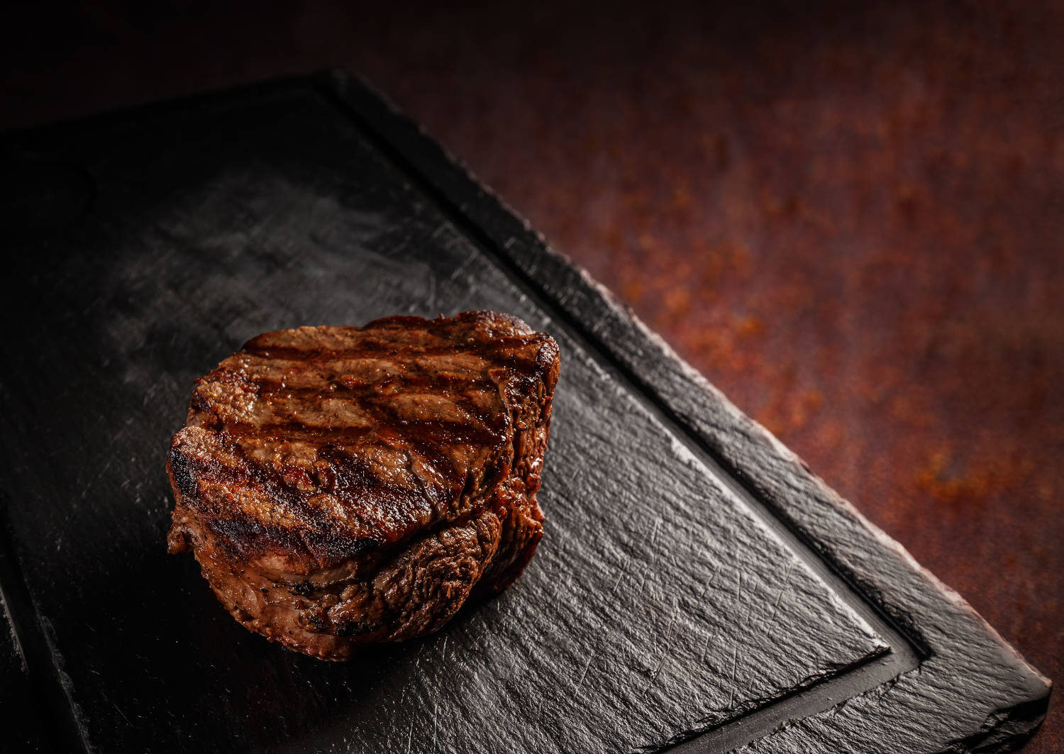 Matured Argentinian ribeye steak on black slate board
