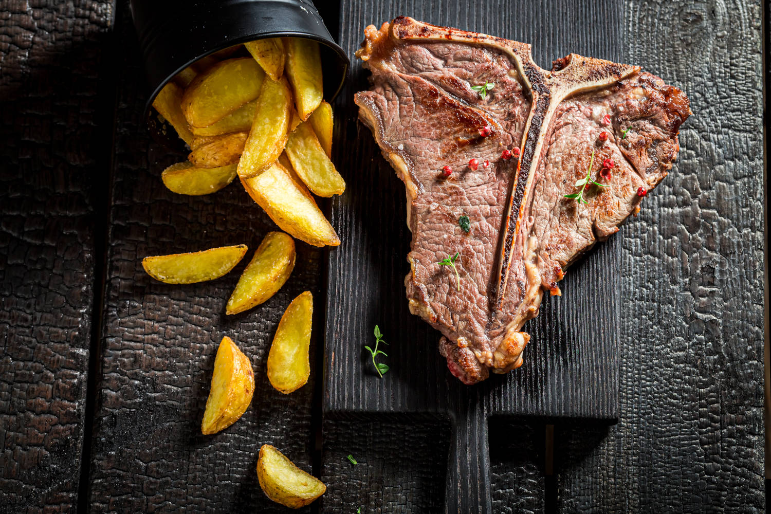 Homemade chips and well done tbone steak with salt on black rock